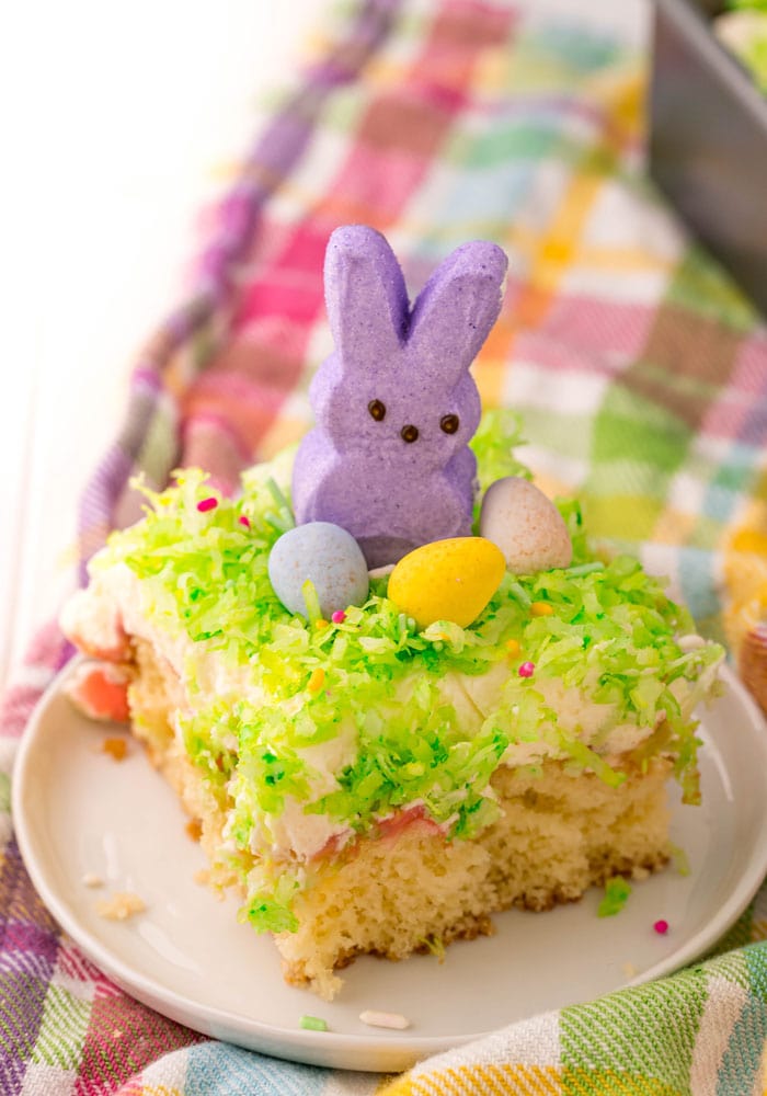A purple Peeps bunny perched on top of a decorated slice of Peeps Poke Cake.