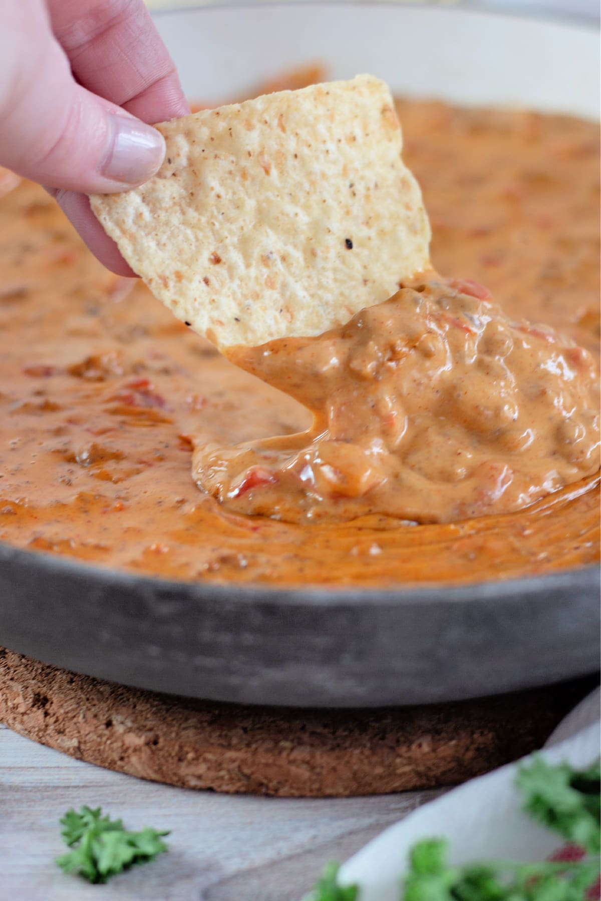 Hand dipping a tortilla chip into rotel dip.
