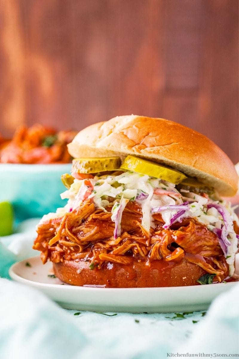 The pulled chicken sandwich on a plate on a blue cloth.