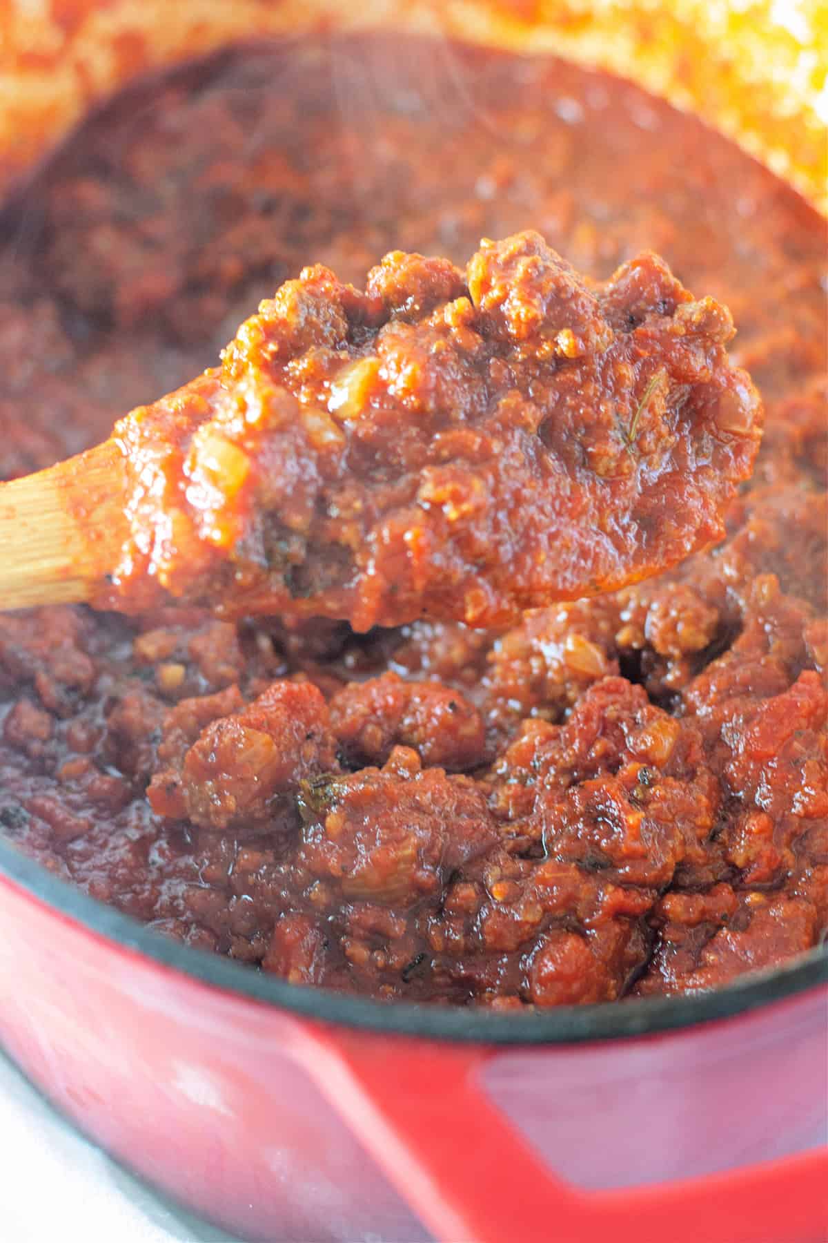 Italian sausage and ground beef are simmered with crushed and fire roasted tomatoes to make this the BEST Spaghetti Meat Sauce recipe. A wooden spoon in spaghetti meat sauce