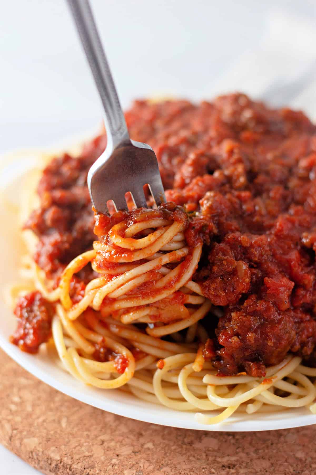 Italian sausage and ground beef are simmered with crushed and fire roasted tomatoes to make this the BEST Spaghetti Meat Sauce recipe. A fork twirling spaghetti with meat sauce