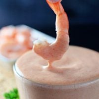 A shrimp is dipped into a bowl of yum yum sauce.