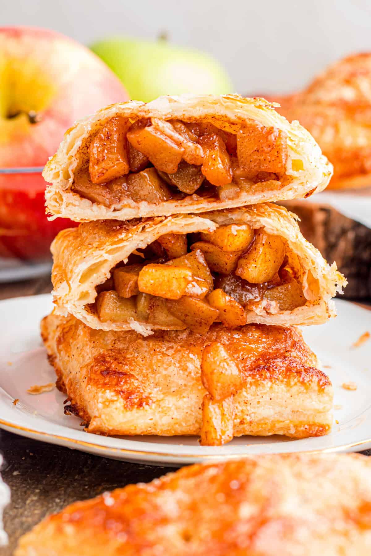Apple Hand Pies stacked on a plate with one opened to show the inside.