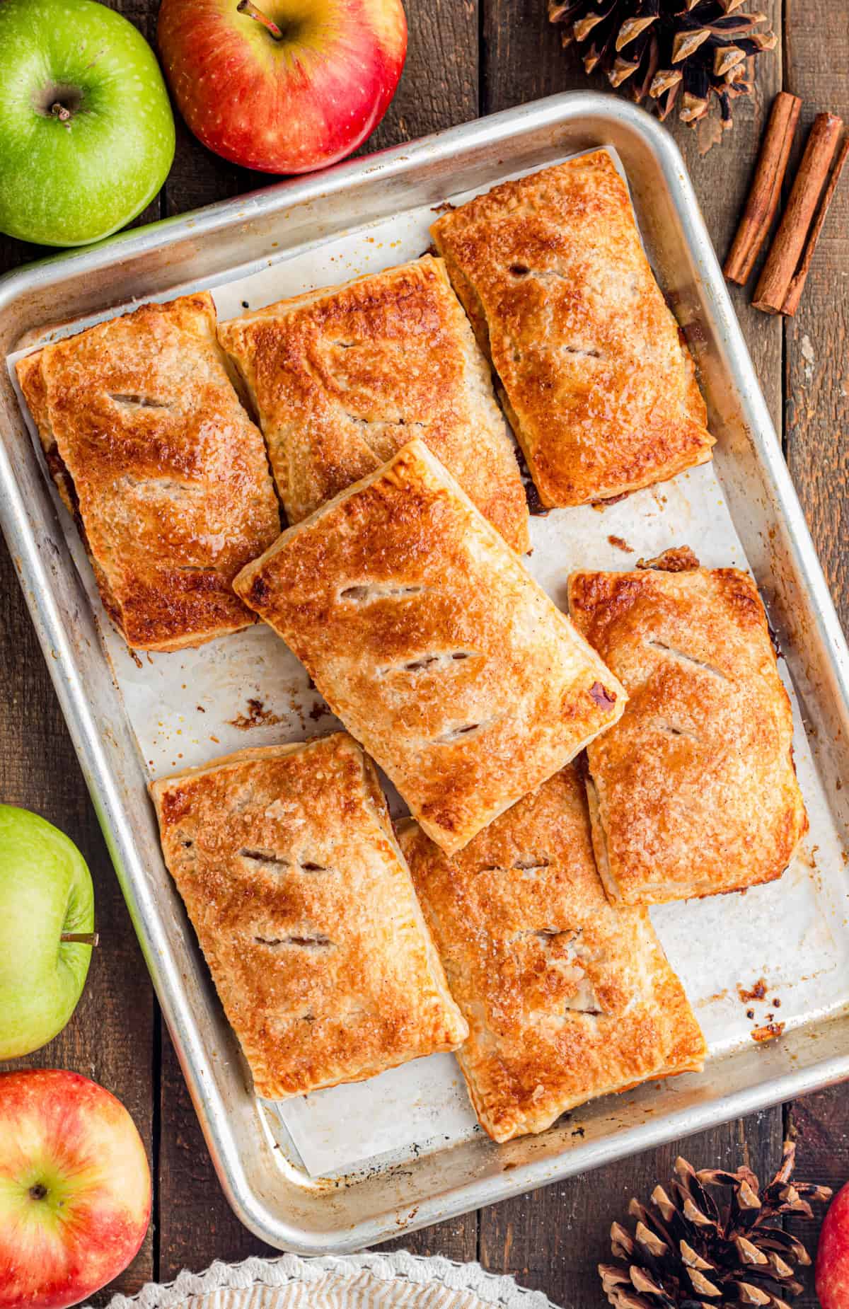 These Apple Hand Pies are filled with gooey apple pie filling wrapped in flaky puff pastry and baked until deeply golden and crisp. baking sheet with baked apple hand pies.