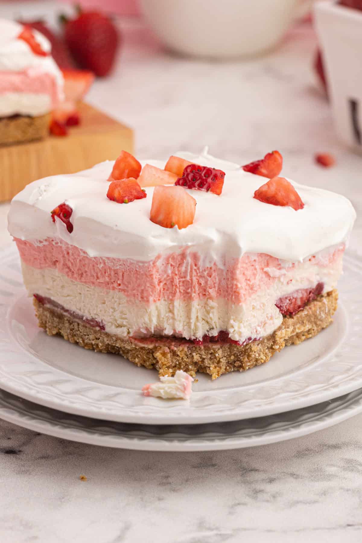 With a cream cheese filling, fresh strawberries, and Cool Whip in a graham cracker crust, Strawberry Delight is an easy no-bake dessert. a slice of Strawberry Delight on a plate