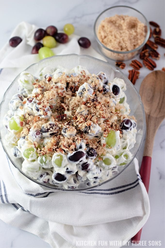 Creamy Grape Salad topped with pecans and brown sugar.