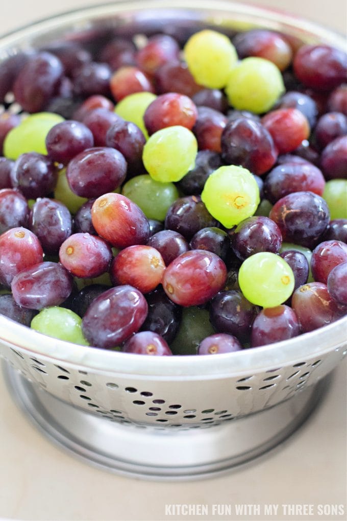 washing red and green grapes in a colander. 