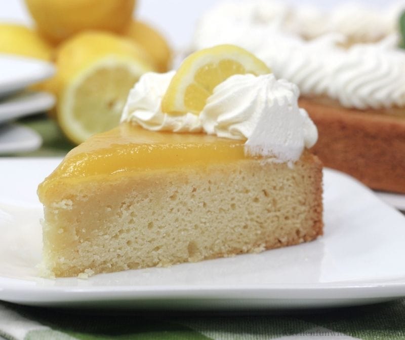 A piece of the cake with some extra lemons on the side.