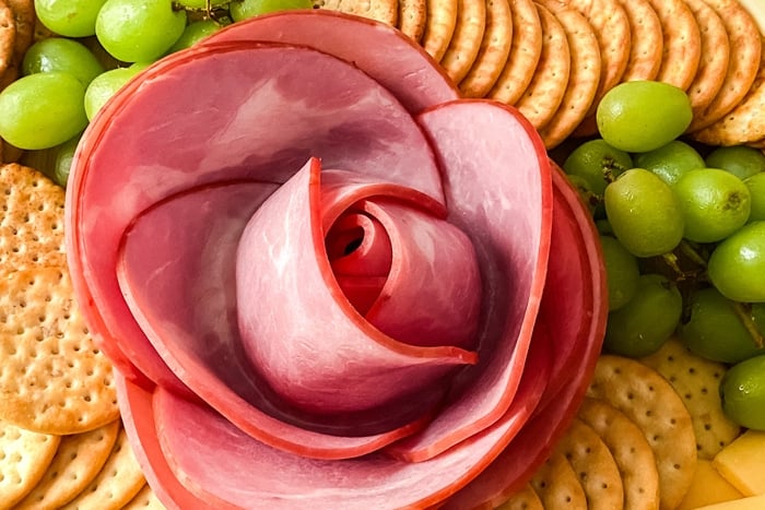 Close up of a ham rose on a meat and cheese board