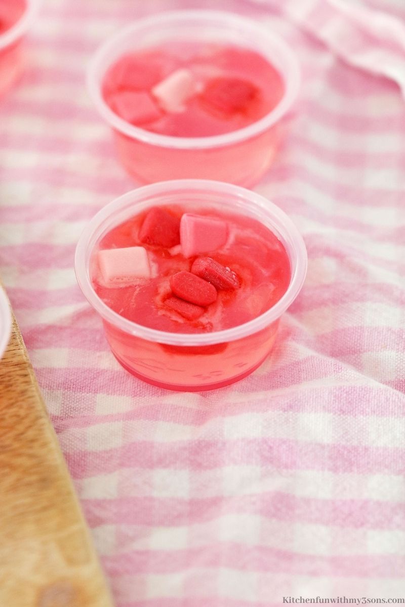 The jello shots on a pink checkered cloth.