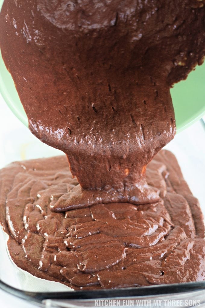 pouring chocolate cake batter into a prepared baking dish.
