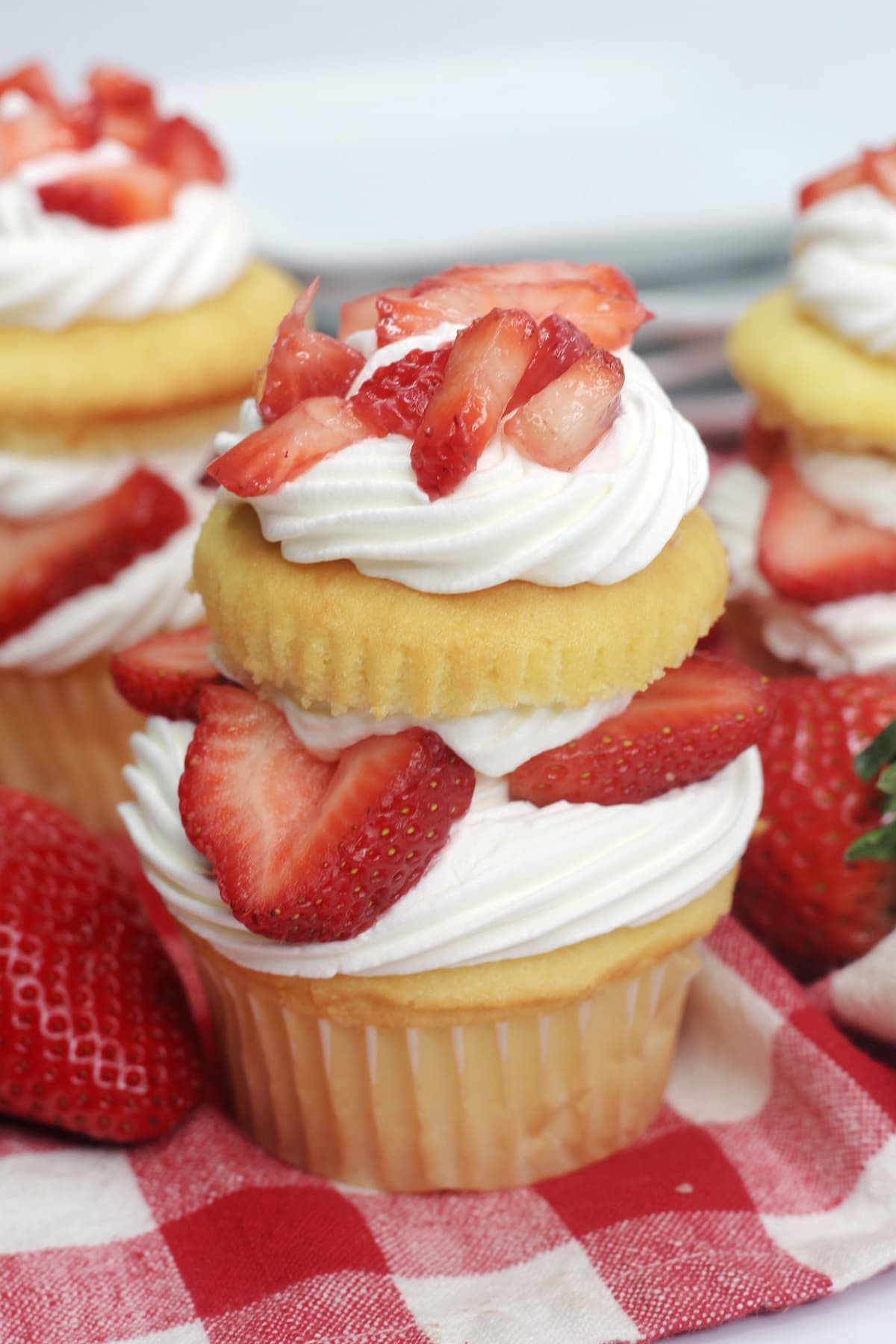 A strawberry shortcake cupcake on a red checkered cloth