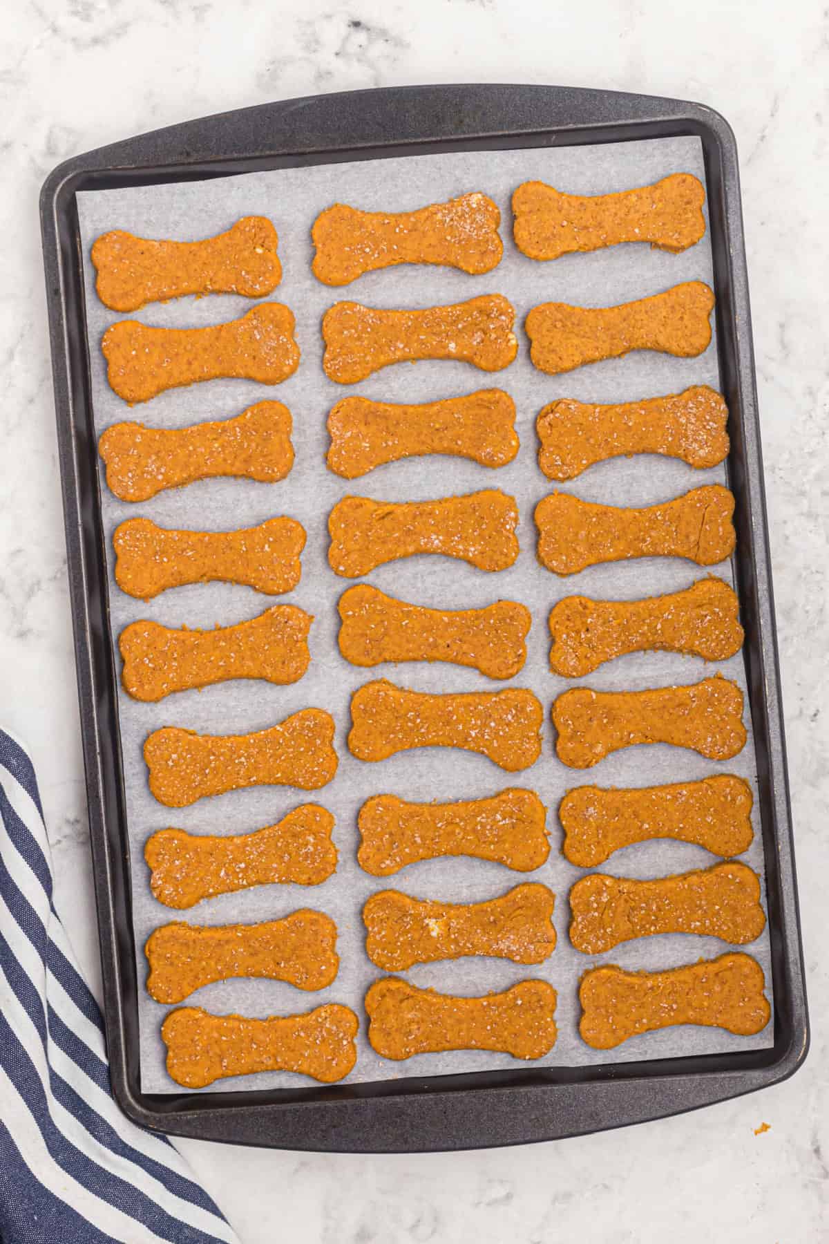 These easy Homemade Dog Treats are made with pumpkin, peanut butter, whole wheat flour, eggs, and a little cinnamon. cut out dough shapes on a cookie sheet.