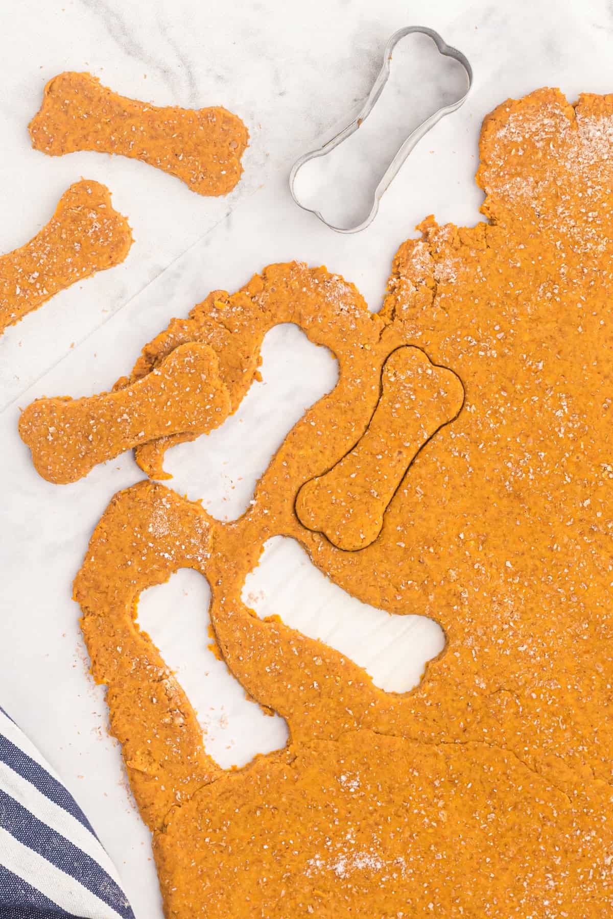 These easy Homemade Dog Treats are made with pumpkin, peanut butter, whole wheat flour, eggs, and a little cinnamon. cutting the dough into dog bone shapes using a cookie cutter.