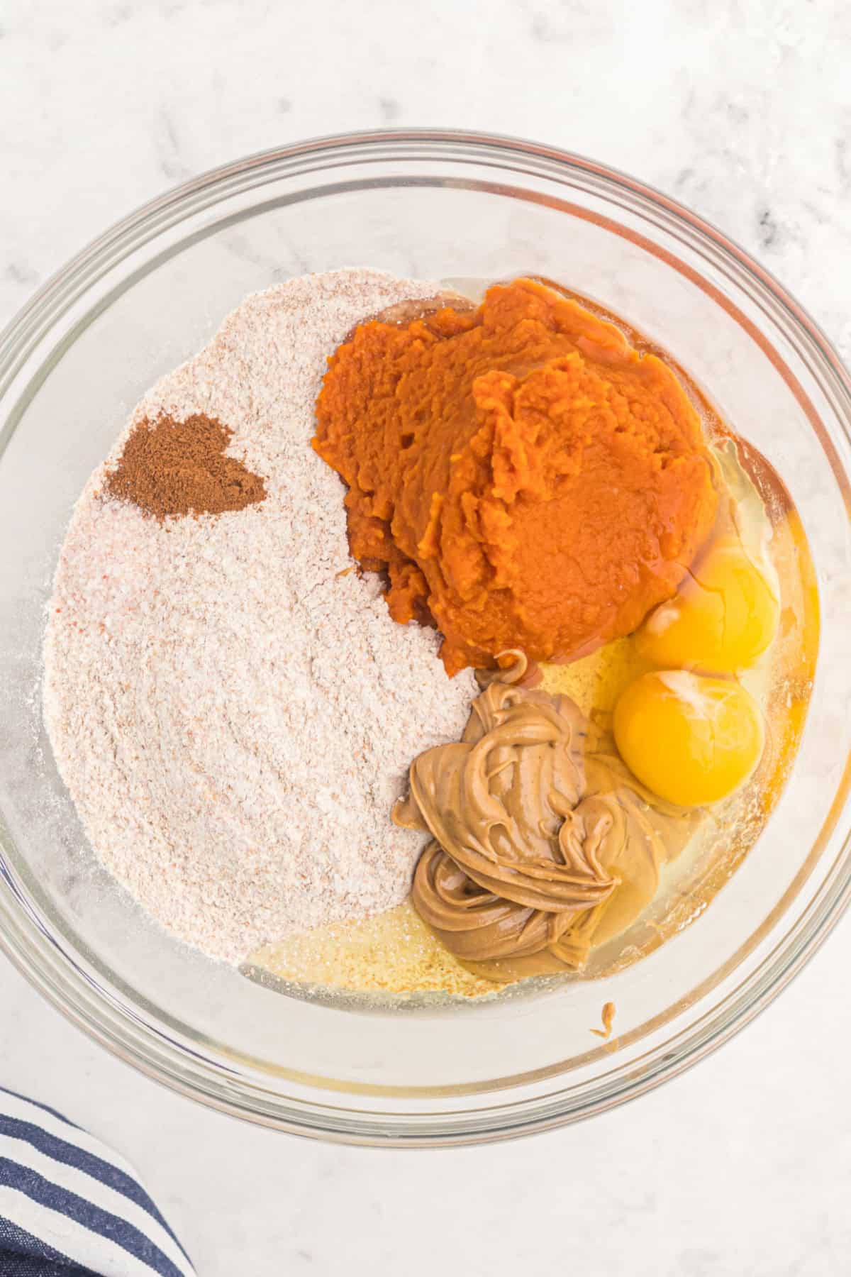 These easy Homemade Dog Treats are made with pumpkin, peanut butter, whole wheat flour, eggs, and a little cinnamon. ingredients for Homemade Dog Treats in a bowl.