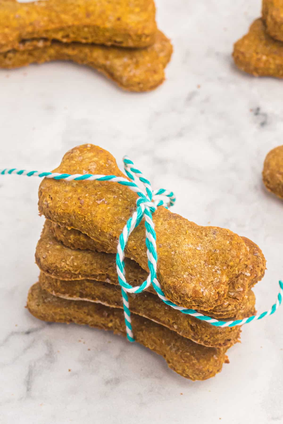 These easy Homemade Dog Treats are made with pumpkin, peanut butter, whole wheat flour, eggs, and a little cinnamon. stacked homemade dog treats with twine for gifting.