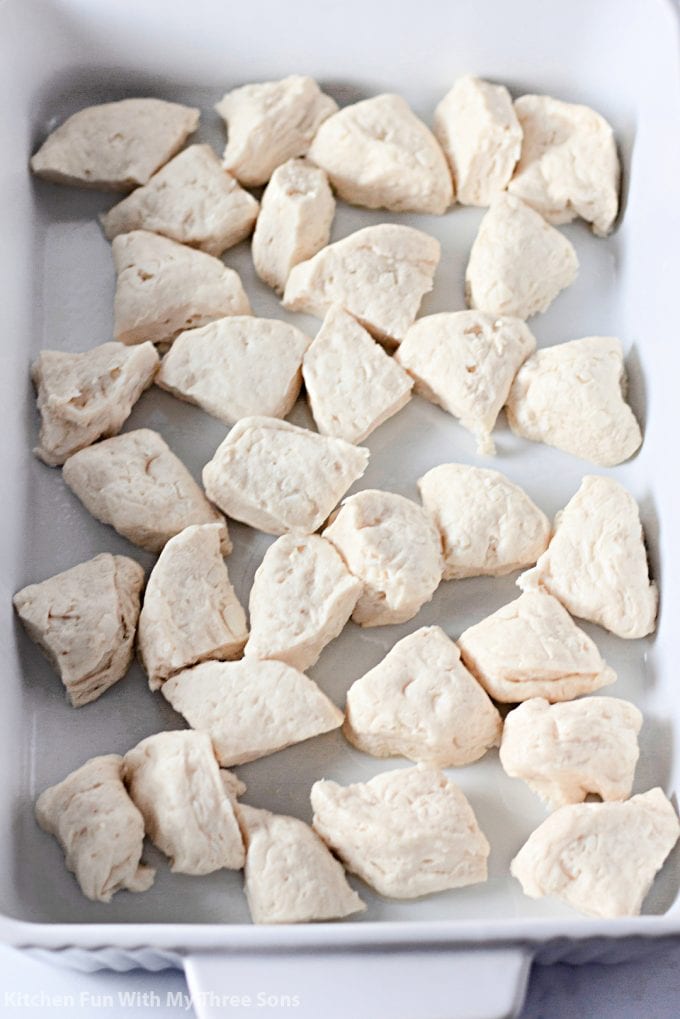 pieces of biscuit dough in a white casserole dish.