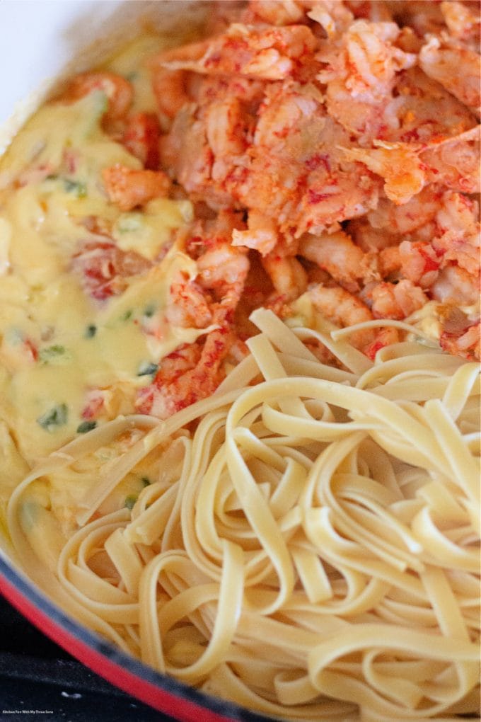 adding the crawfish and fettuccine to the cheese sauce.