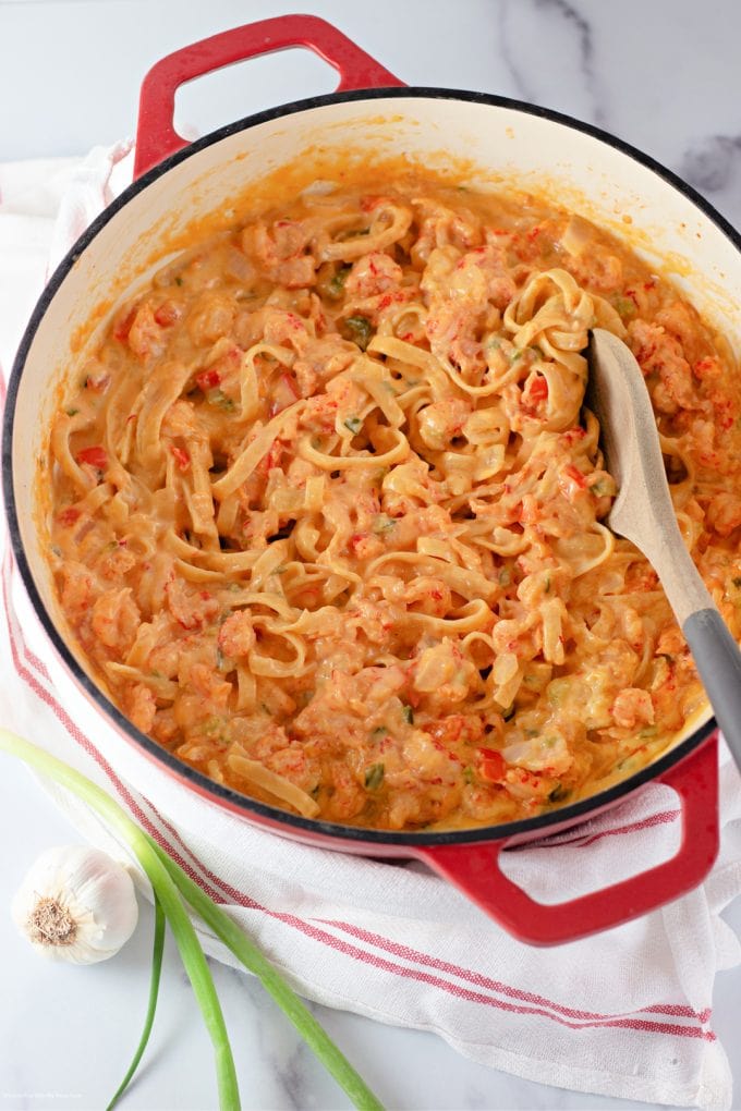red Dutch oven with Crawfish Fettuccini and a wooden spoon.