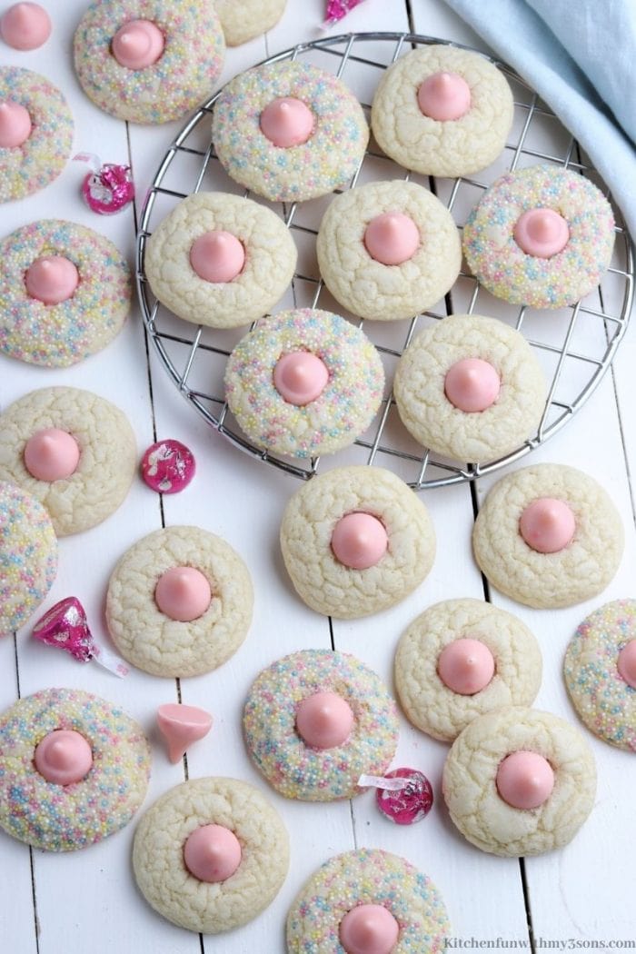 Overhead view of assorted strawberry kiss cookies on a tabletop, with some cookies on a round wire rack.