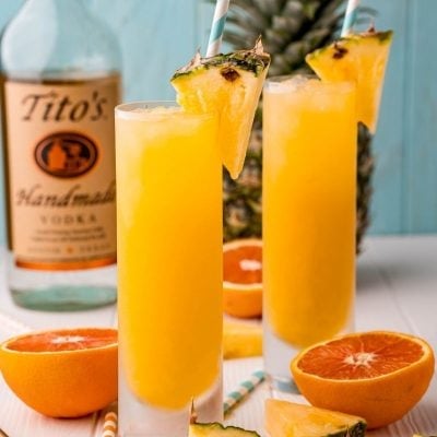 The cocktail with liquor and a whole pineapple behind it.