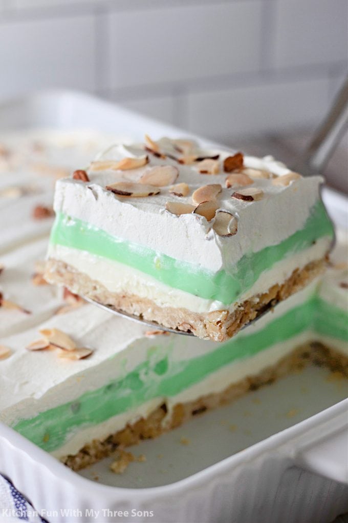 lifting a slice of Pistachio Lush Dessert with a spatula.