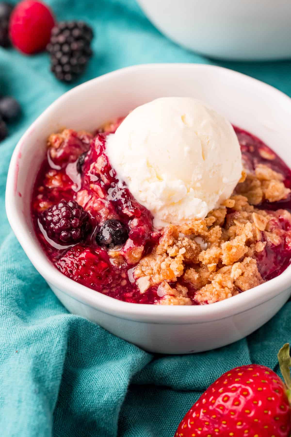 Mixed Berry Crisp in a bowl topped with vanilla ice cream