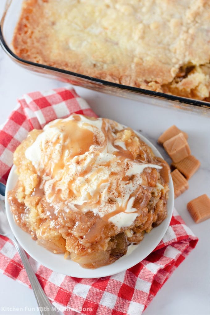 Caramel Apple Dump Cake topped with ice cream and caramel sauce.