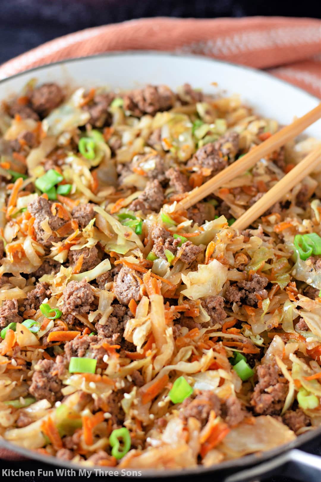 Ground beef and coleslaw in a large bowl with a pair of chopsticks