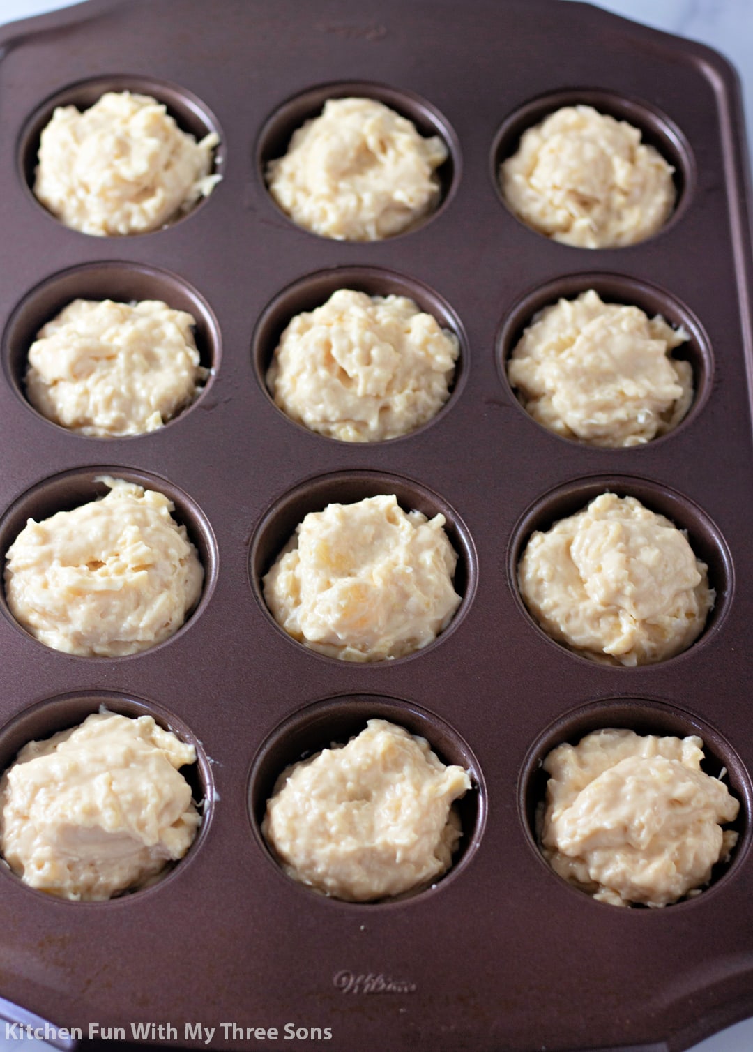 Unbaked tropical muffins in a muffin tin.