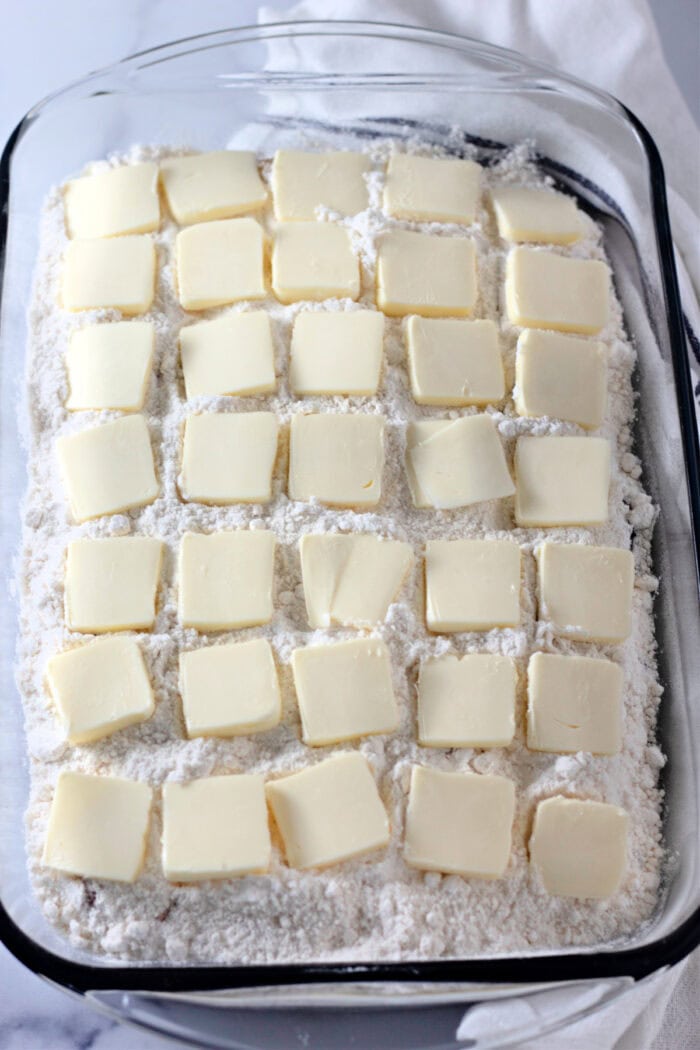 slices of butter on top of dry cake mix in a pan