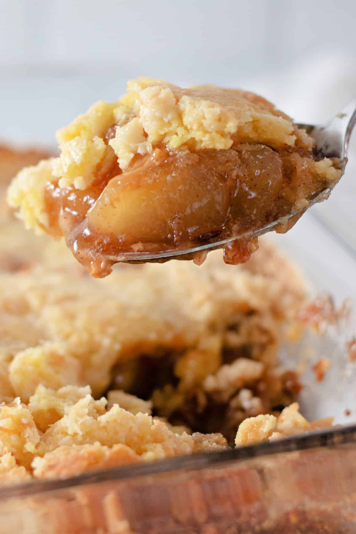 lifting Caramel Apple Dump Cake out of a plan with a spoon