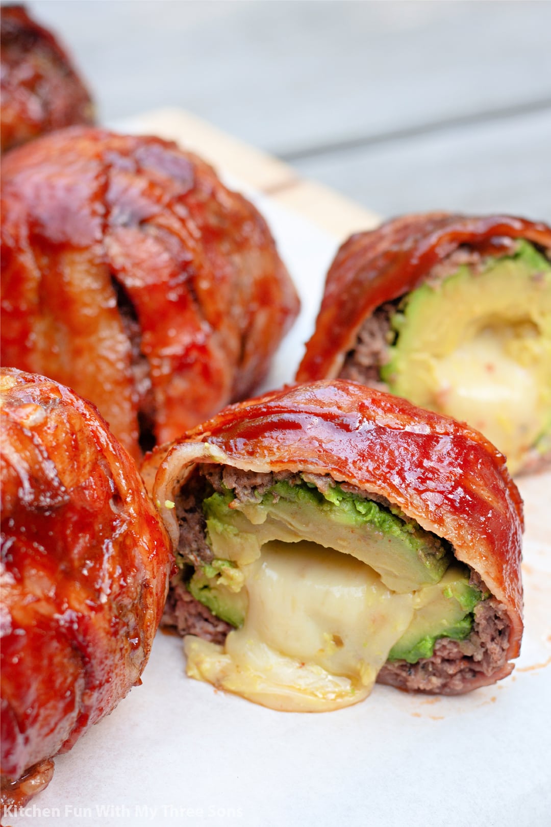 a BBQ Bacon Wrapped Stuffed Avocado sliced open with cheese oozing out.