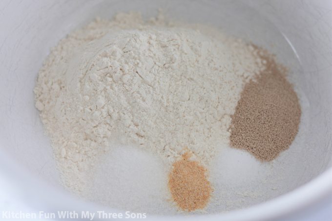 mixing together flour, yeast, sugar, and salt to make dough.