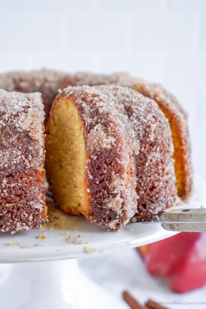 Taking a piece of apple cider donut cake out of the whole.