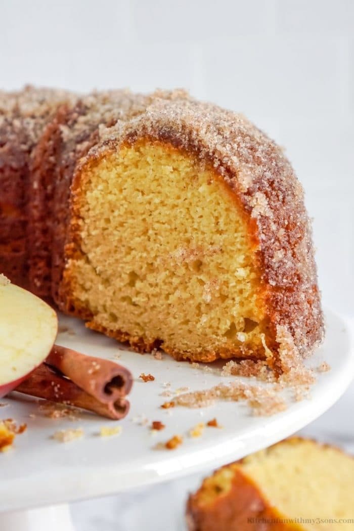 The apple cider donut cake with a piece cut out of it.