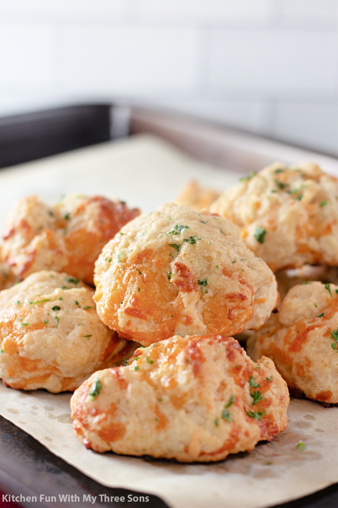 Cheddar bay biscuits piled on a baking sheet.
