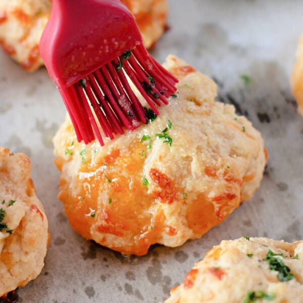 A rubber basting brush coats the tops of Cheddar Bay Biscuits with garlic butter.
