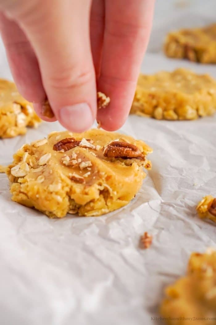 Adding pecans on top of the cookies.