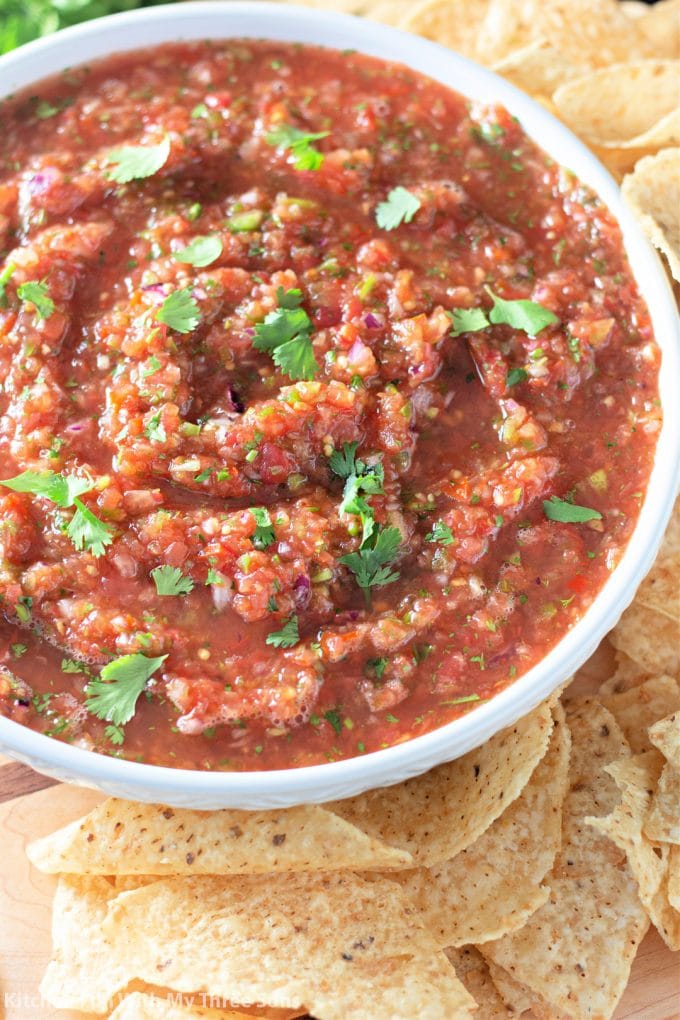 a white bowl of Homemade Salsa surrounded with tortilla chips.