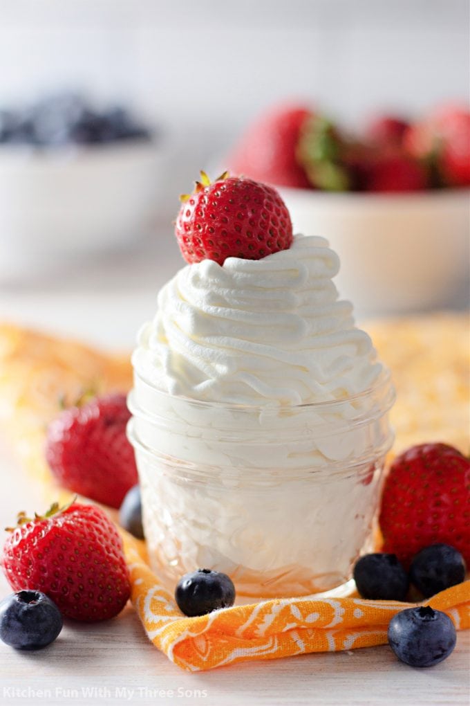 Whipped Cream Recipe in a clear glass jar with strawberries.