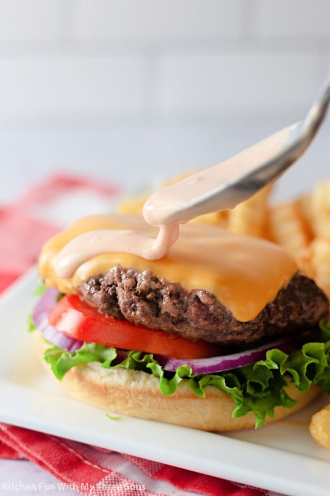 Drizzling Burger Sauce onto a cheeseburger.