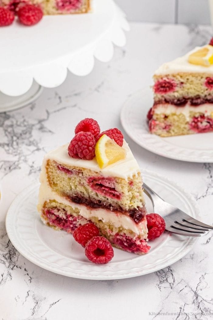 A slice of the cake topped with raspberries and lemon.