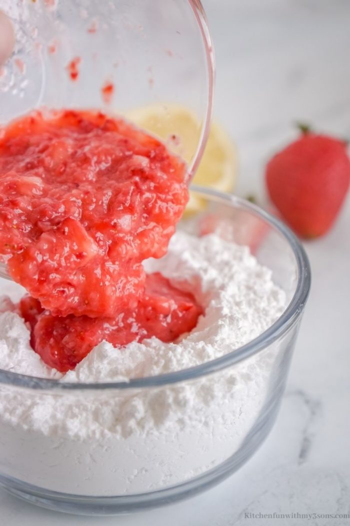 Combining the strawberries and powdered sugar.