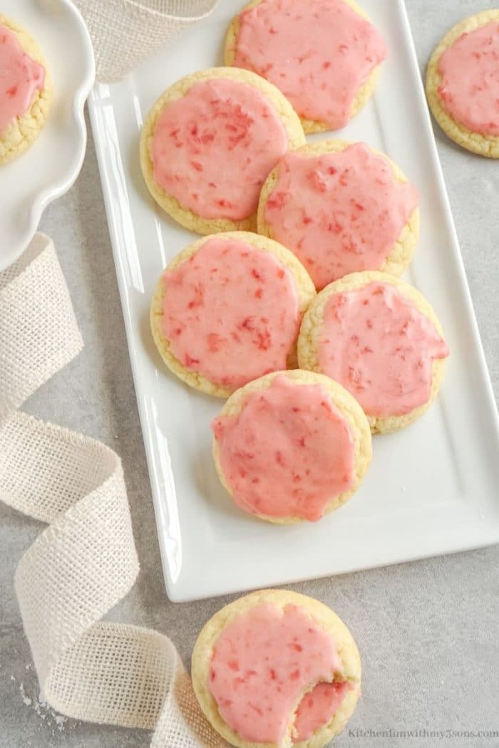 Overhead view of assorted strawberry sugar cookies on a rectangular serving dish.