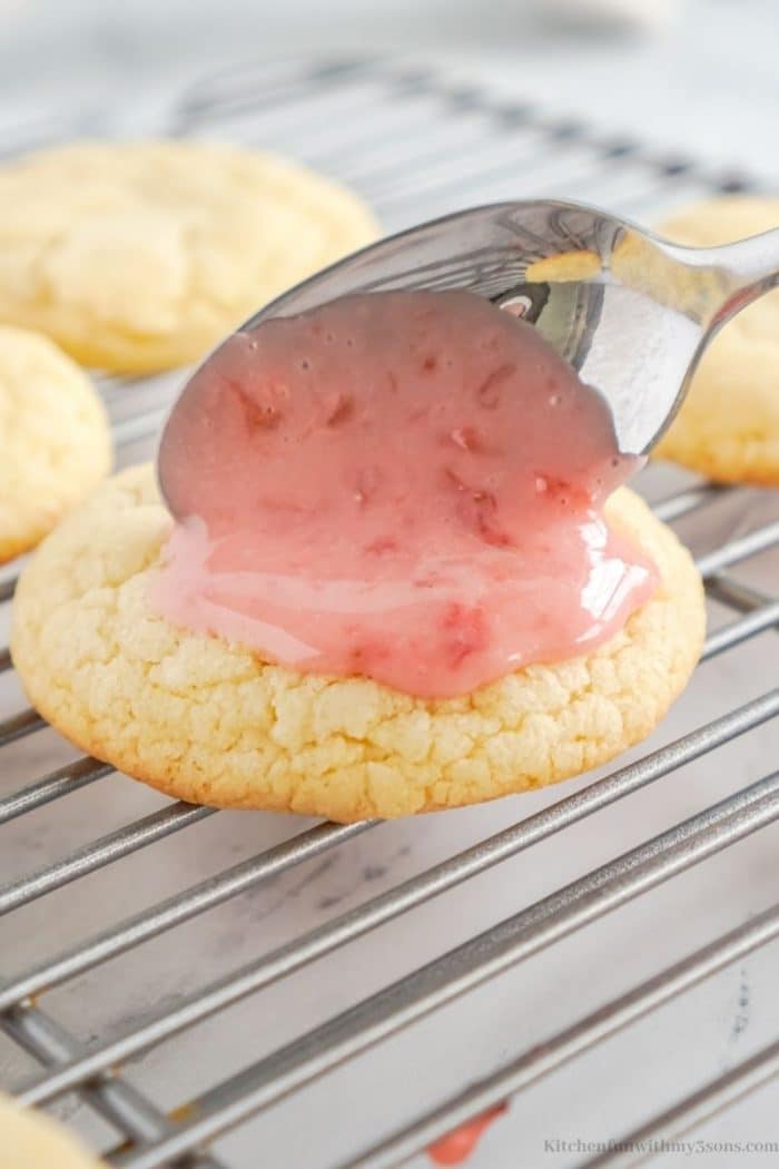 Adding the strawberry glaze on top of the sugar cookies.