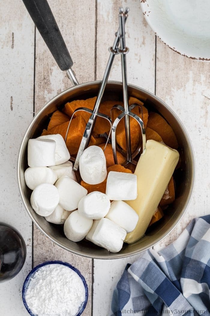 Marshmallows being added to a pot of boiled sweet potatoes.