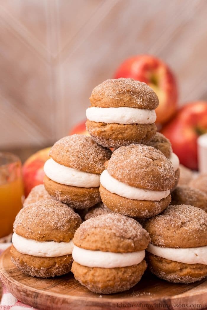 A pile of apple whoopie pies on a table cloth.