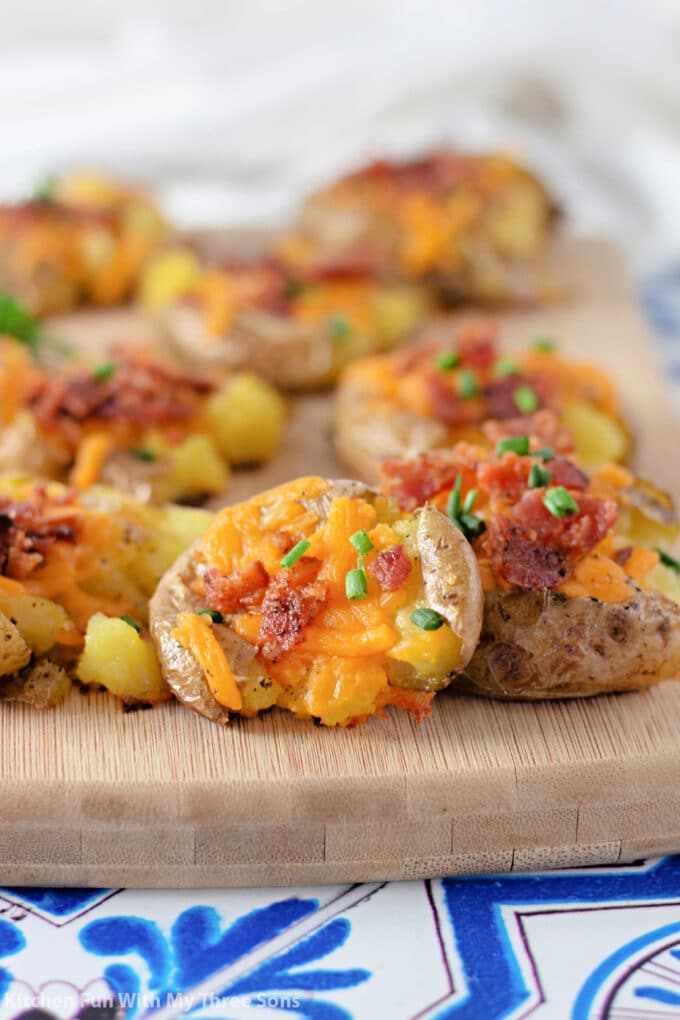 Bacon Cheddar Smashed Potatoes on a wooden cutting board.