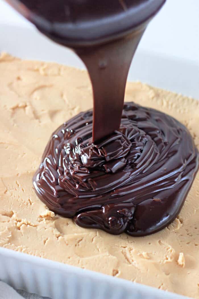 Pouring chocolate ganache over the peanut butter filling